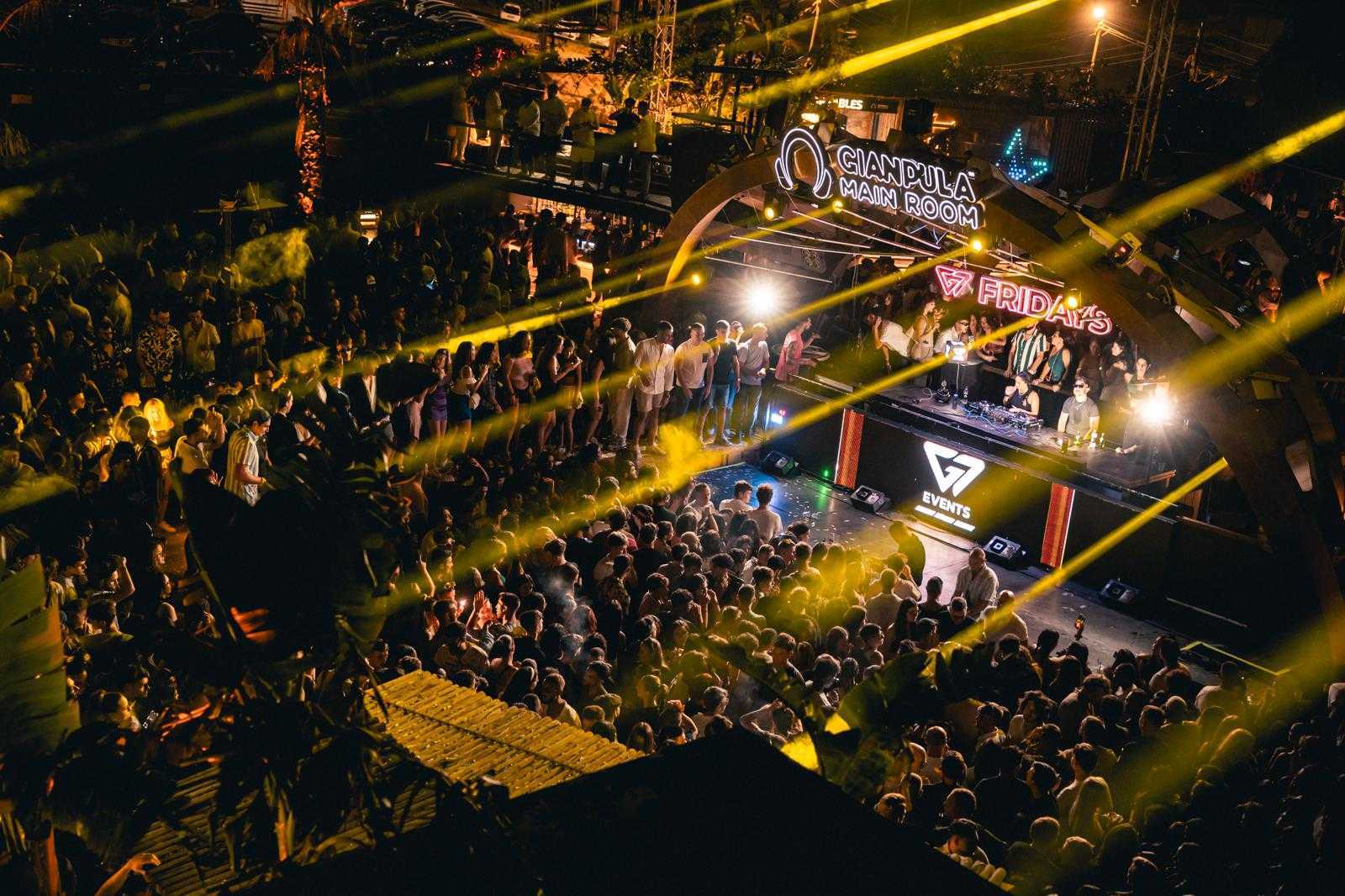 Nightclub crowd with a DJ, yellow stage lights, and "Gianpula Main Room" sign.