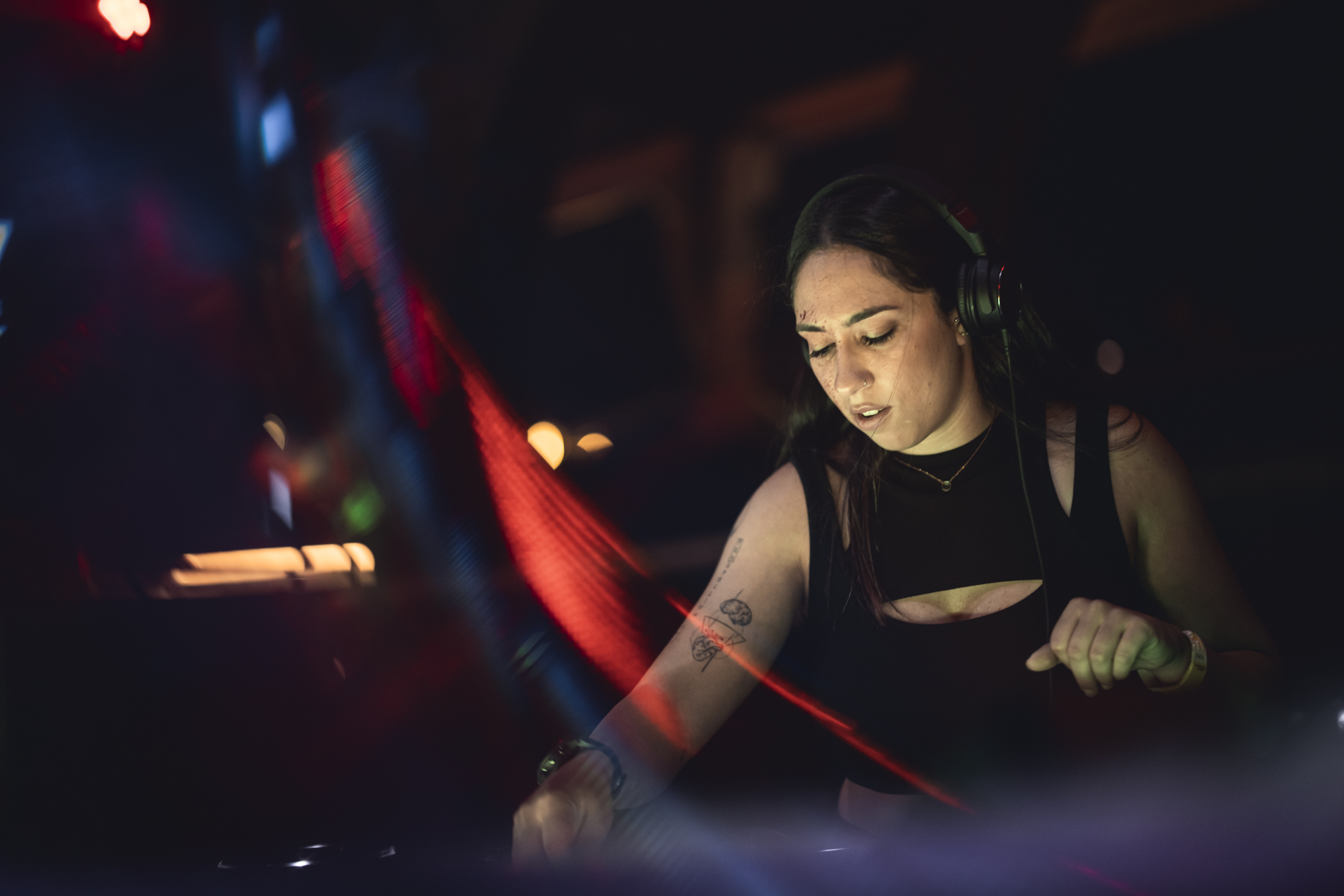 Female DJ in black dress performing at a night event.