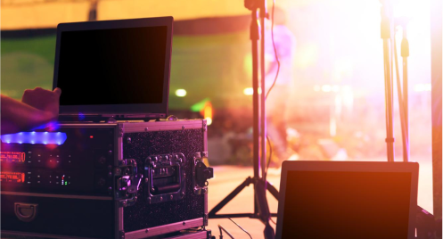 Stage with laptops and audio equipment, bright lights suggesting a live event.