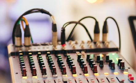 Close-up of an audio mixing console with lights and knobs.